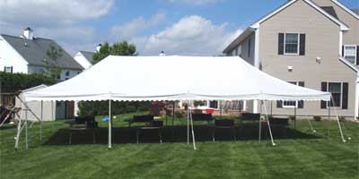 40x100 white top rental tent staked in grass.